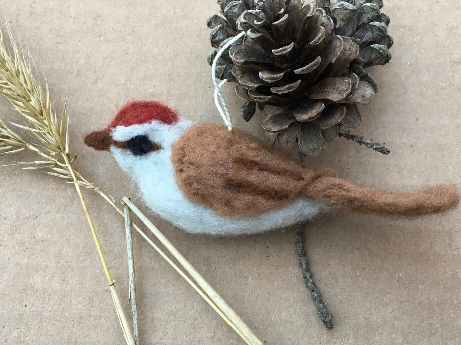 image of a needle felted chipping sparrow, surrounded by natural found objects