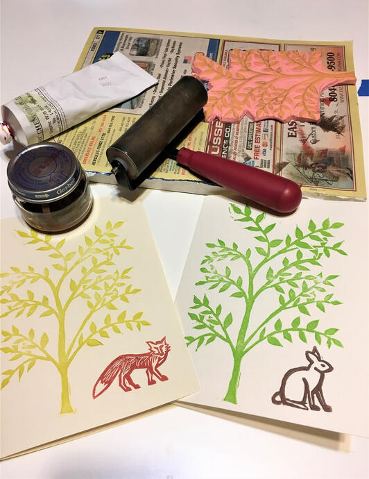 image of two hand-printed cards, surrounded by printmaking tools