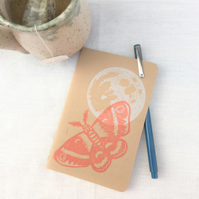 image of a hand-printed notebook with a pen and a mug of tea